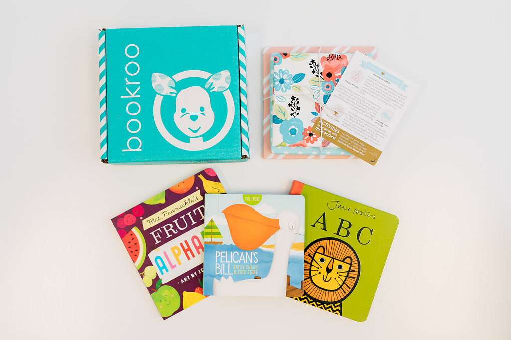 A picture of an opened bookroo subscription book box displaying its contents- several books and an insert. 